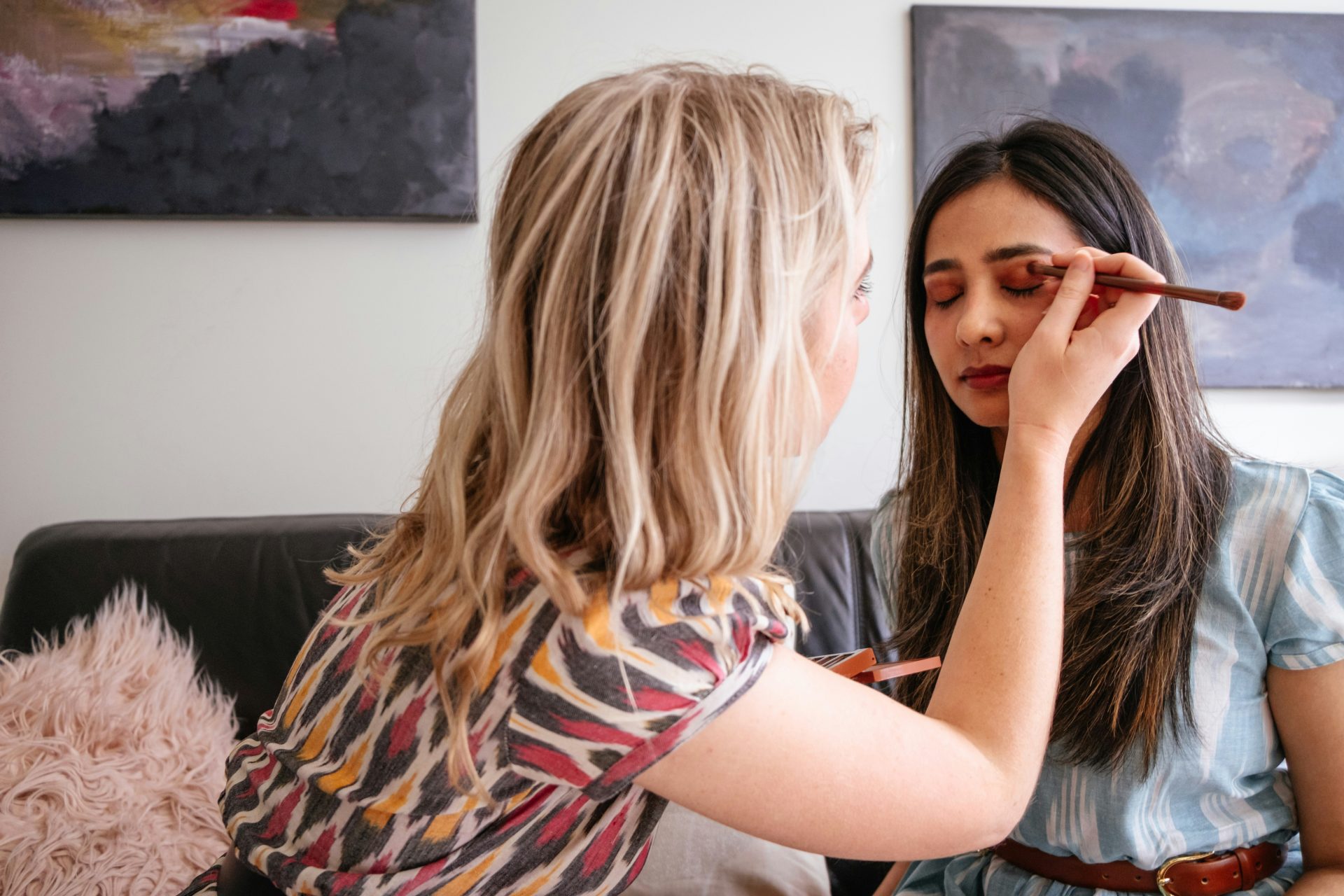 Artist carefully applying eyeshadow on model’s eyelids.