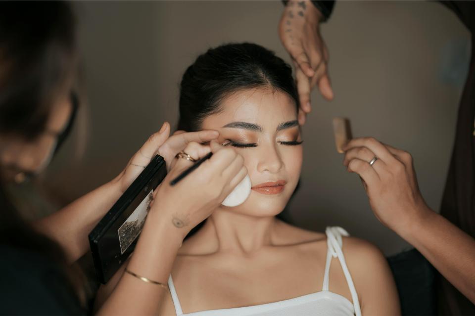 Elegant woman getting makeup done for event.