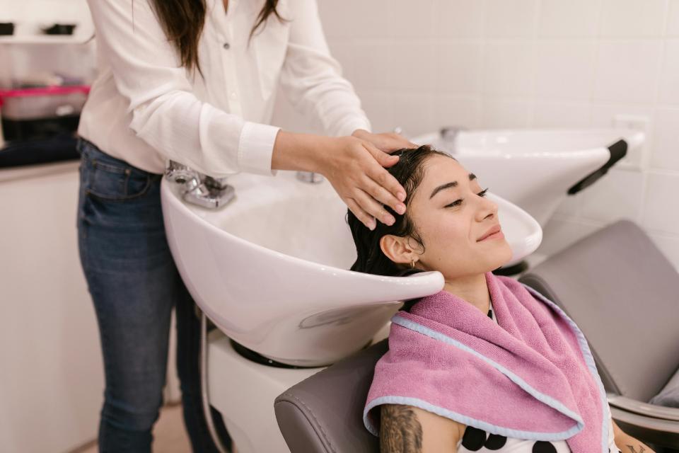 Hairdresser gently washing client’s hair relaxingly.