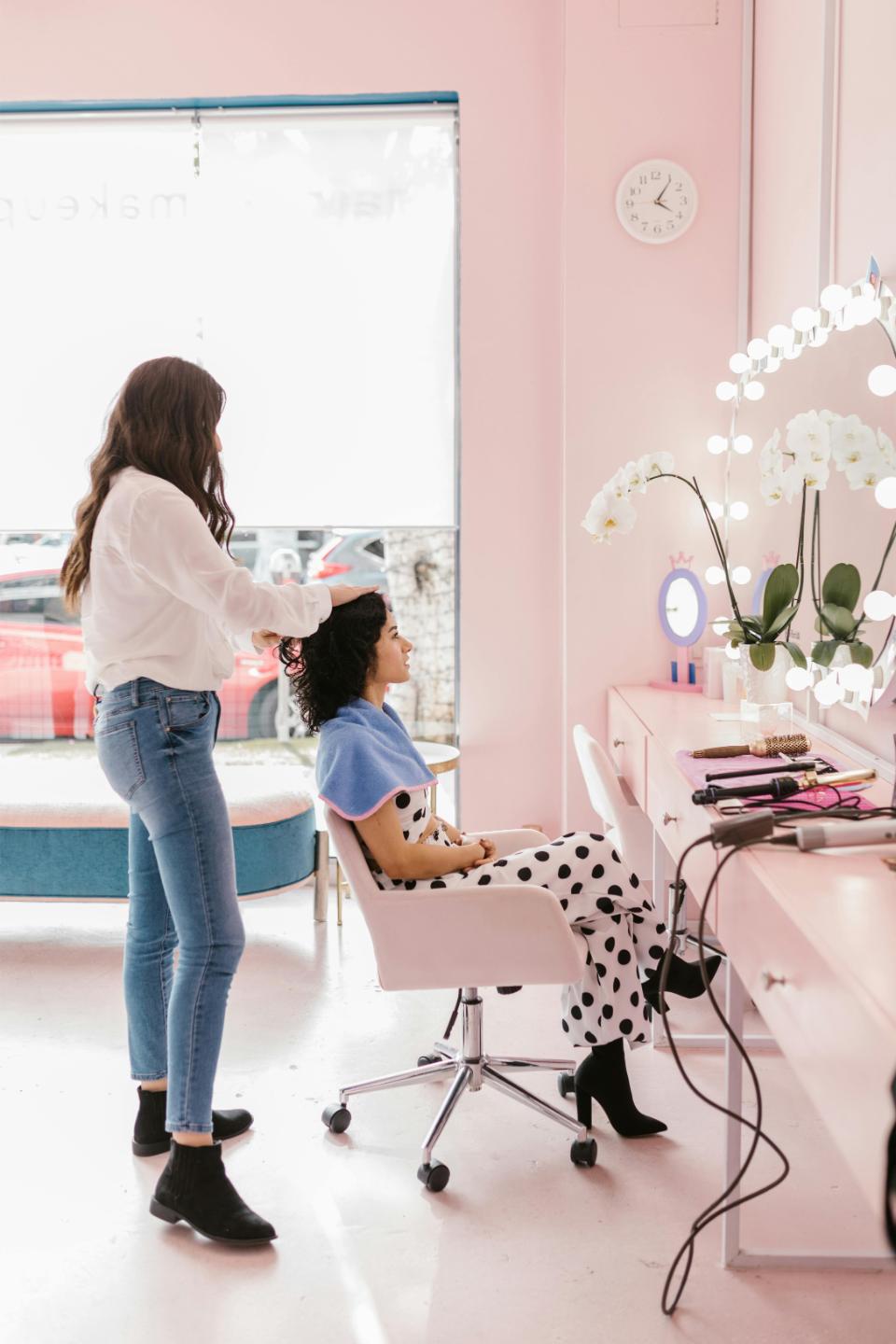 Stylist arranging curls at pink salon